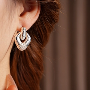 Close-up of elegant rose gold and silver geometric earrings on a female model
