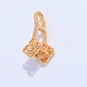 Close-up of golden hollow clover pendant clasp with intricate geometric patterns