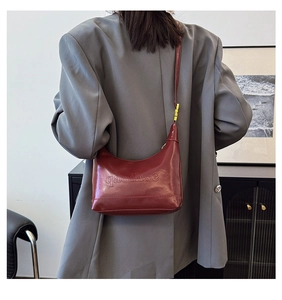 Close-up of wine red leather shoulder bag with gold hardware and embossed lettering detail