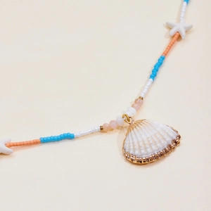 Detail of 18K gold stainless steel necklace with shell pendant and colorful sea beads