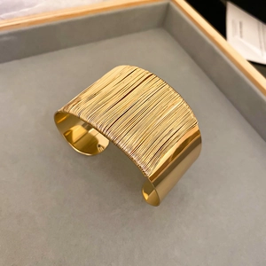 Detailed view of golden twisted wide cuff bracelet with smooth and textured finish