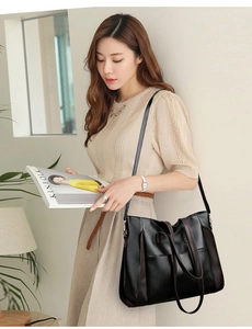 Minimalist black soft leather tote bag worn by a model in a modern office setting