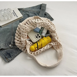 Flat lay of an off-white woven tote bag with daily essentials on a white background