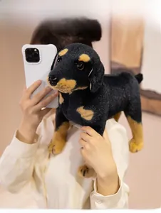 Mirror selfie showing the medium size of a lifelike black and tan plush puppy dog toy