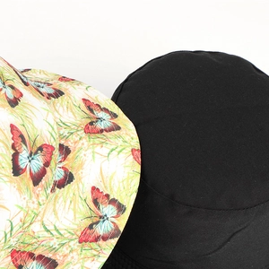 Detail view of double-sided bucket hats in black and butterfly print pattern