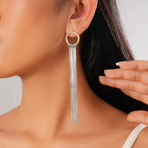 Detail of 18K gold-plated round hoop earrings with long silver tassels on a female model