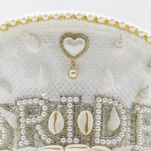 Detailed view of bride captain hat with white sequins, shells, pearls and rhinestone bride text