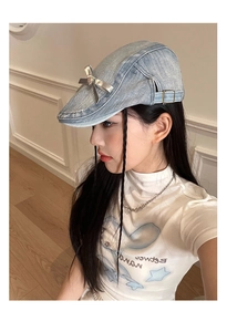 Side view of light blue denim beret featuring a silver bow and adjustable metal buckle