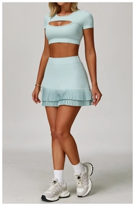 Detail of mint green two-piece yoga set with cutout crop top and pleated mini skirt