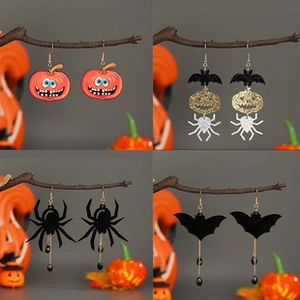 Macro detail of Halloween pumpkin, spider and bat earrings hanging on a dead wood branch