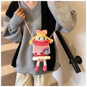 Detail of pink knitted crossbody bag with cartoon doll face and mini purple bear charm