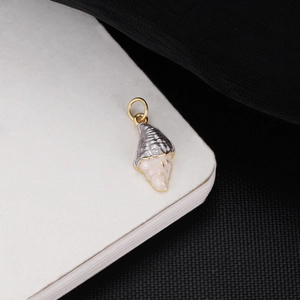 Detailed macro view of conch shell pendant with gray metallic texture and gold ring