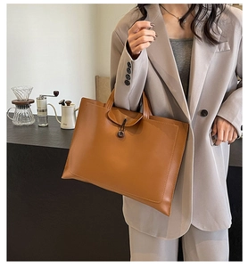 Close-up of brown retro tote bag with buckle flap and refined stitching detail
