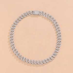 Top view of silver Cuban link necklace with sparkling rhinestones on beige surface