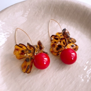 Gros plan de boucles d'oreilles fleur écaille avec grands pendentifs perles rouges