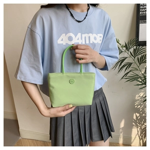 Détail d'un sac seau en nylon vert clair avec logo rond et poignée circulaire élégante