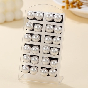 Set of 12 pairs of white round faux pearl earrings displayed on an elegant acrylic stand