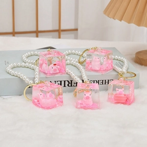 Detailed view of pink resin pig keychains with liquid glitter and white pearl wristlet