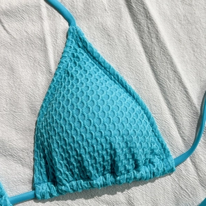 Dettaglio del top bikini azzurro con trama a nido d'ape 3D e lacci sottili regolabili