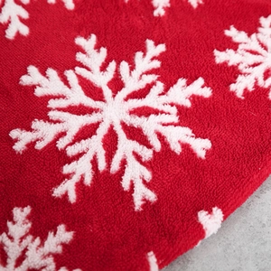 Red plush Christmas tree skirt featuring white snowflake patterns and soft velvet texture