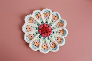 Top view of handmade colorful crochet flower coaster with gradient yarn knit texture