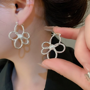 Macro detail of silver flower earrings with central pearl and hollow metal petals