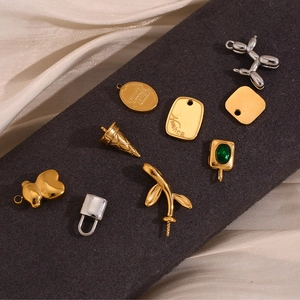 Detailed flat lay of 18K gold plated charms including balloon dog and emerald pendant