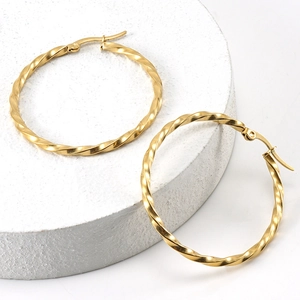 Macro detail of 18K gold plated stainless steel hoop earrings with twisted design on white stand