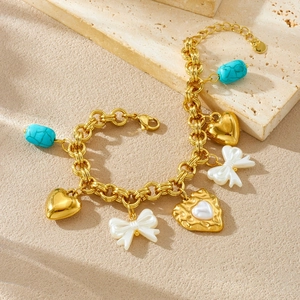 Gold heart pendant bracelet with pearl bow and turquoise beads on stone surface