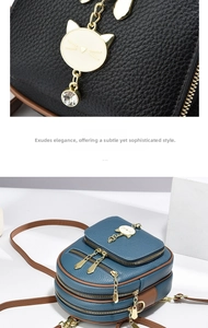 Detailed view of lychee-textured leather backpack with gold cat charm and dual zip layers