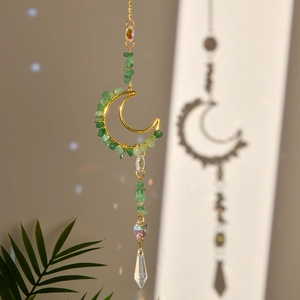 Detail of golden moon frame with green stone chips and faceted crystal prism pendant