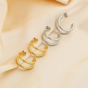 Macro shot of gold and silver double-layered C-shaped earrings on soft silk fabric