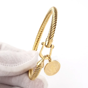 Detailed shot of golden twisted rope bracelet with U-shaped clasp and St. Benedict medal