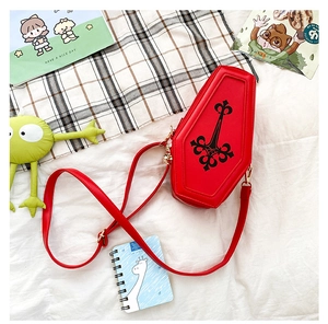 Macro view of a red coffin-shaped crossbody bag with gothic patterns and gold buckle