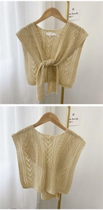 Detailed close-up of hollow knit shawl with tie-front design on wooden hanger