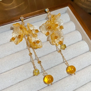 Detailed view of amber resin floral tassel earrings with gold chain and crystals