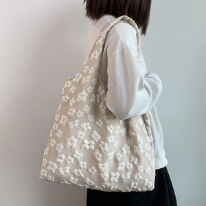 Detail of floral lace embroidery on a beige canvas tote bag with a soft drape design