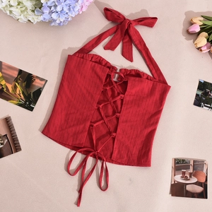 Dettaglio del crop top rosso allacciato al collo con lacci frontali e tessuto a coste