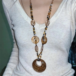 Bohemian long beaded necklace with large leopard print ring pendant on white knit sweater