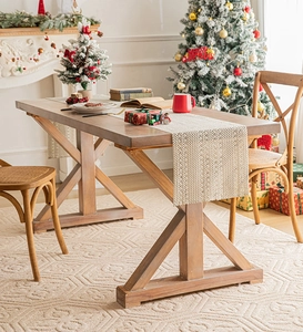 Close-up of a woven beige table runner on a rustic brown wooden table with X-shaped legs