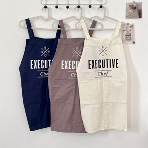 Detail view of cotton linen aprons showing front pockets and Executive Chef lettering