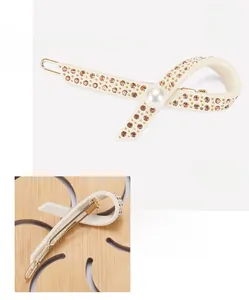 Details von beigefarbener Acetat-Schleife mit Strasssteinen und Perle für die Haare