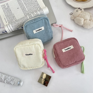 Macro detail of corduroy makeup pouches in pastel blue, cream white, and rose pink