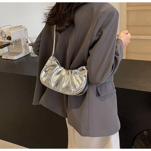 Silver pleated cloud bag on model showing size and metallic finish in chic interior