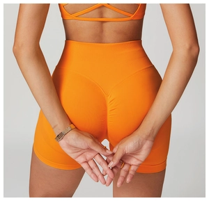 Close-up of bright orange high-waisted fitness shorts with seamless ribbed texture