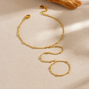 Elegant gold plated stainless steel finger bracelet chain with beads on sand background