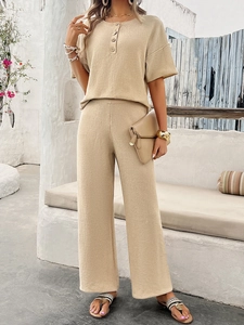 Beige knitted two-piece set featuring short sleeve top and wide leg pants in a scenic setting