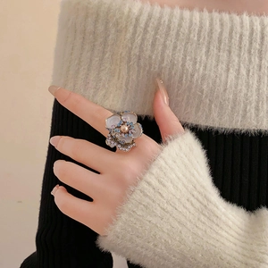 Detail of vintage flower ring with layered petals, central pearl and colorful crystals