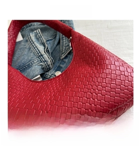 Detailed view of red woven leather texture on a stylish half-moon hobo shoulder bag