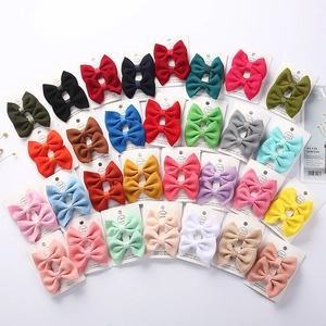 Multiple colorful waffle fabric bow hair clips arranged on handmade display cards